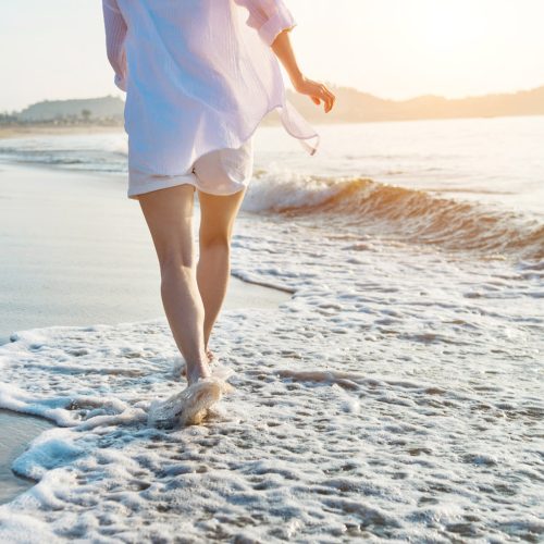 Woman leg walking on beach.